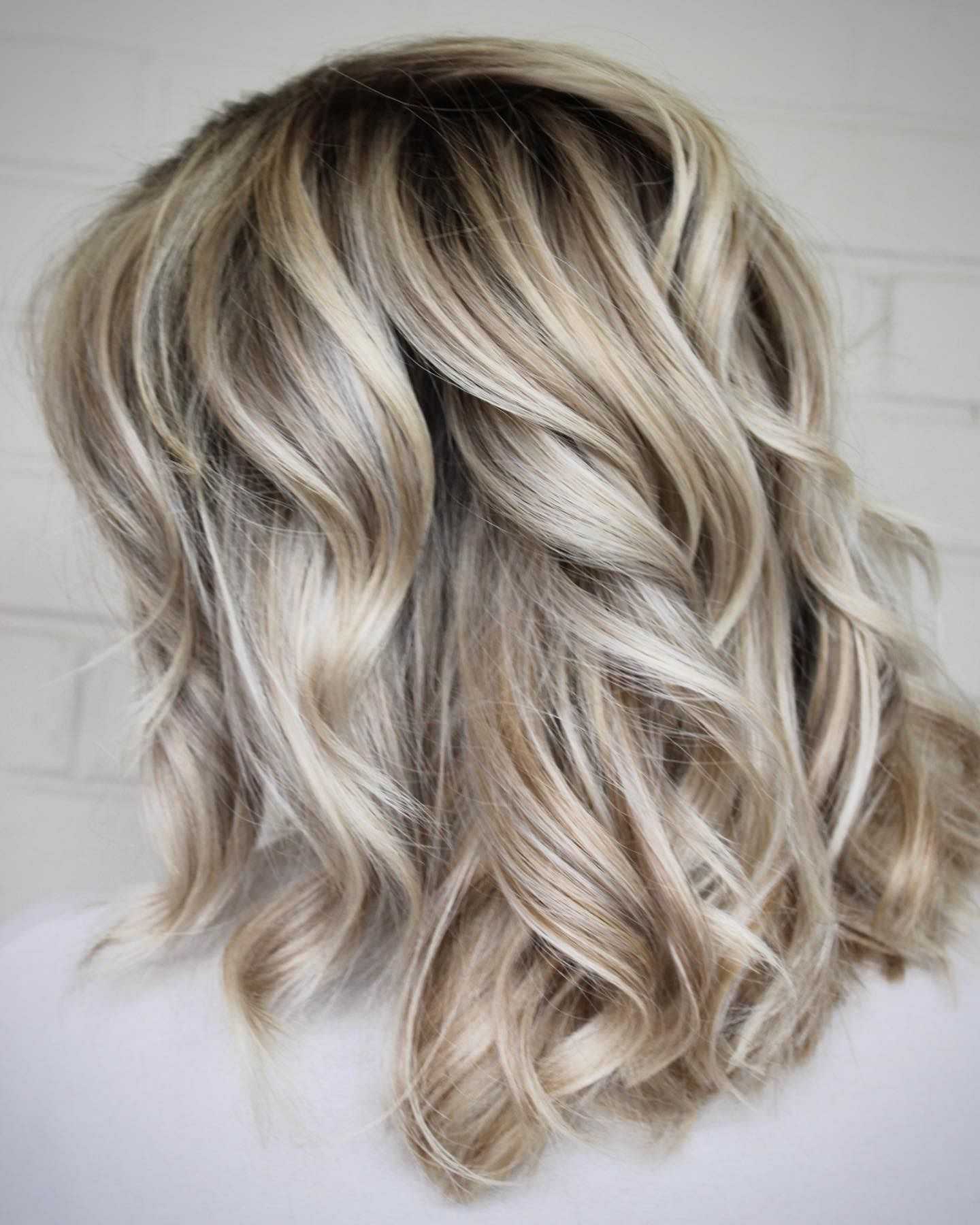 Wavy balayage hairstyle with blond highlights.