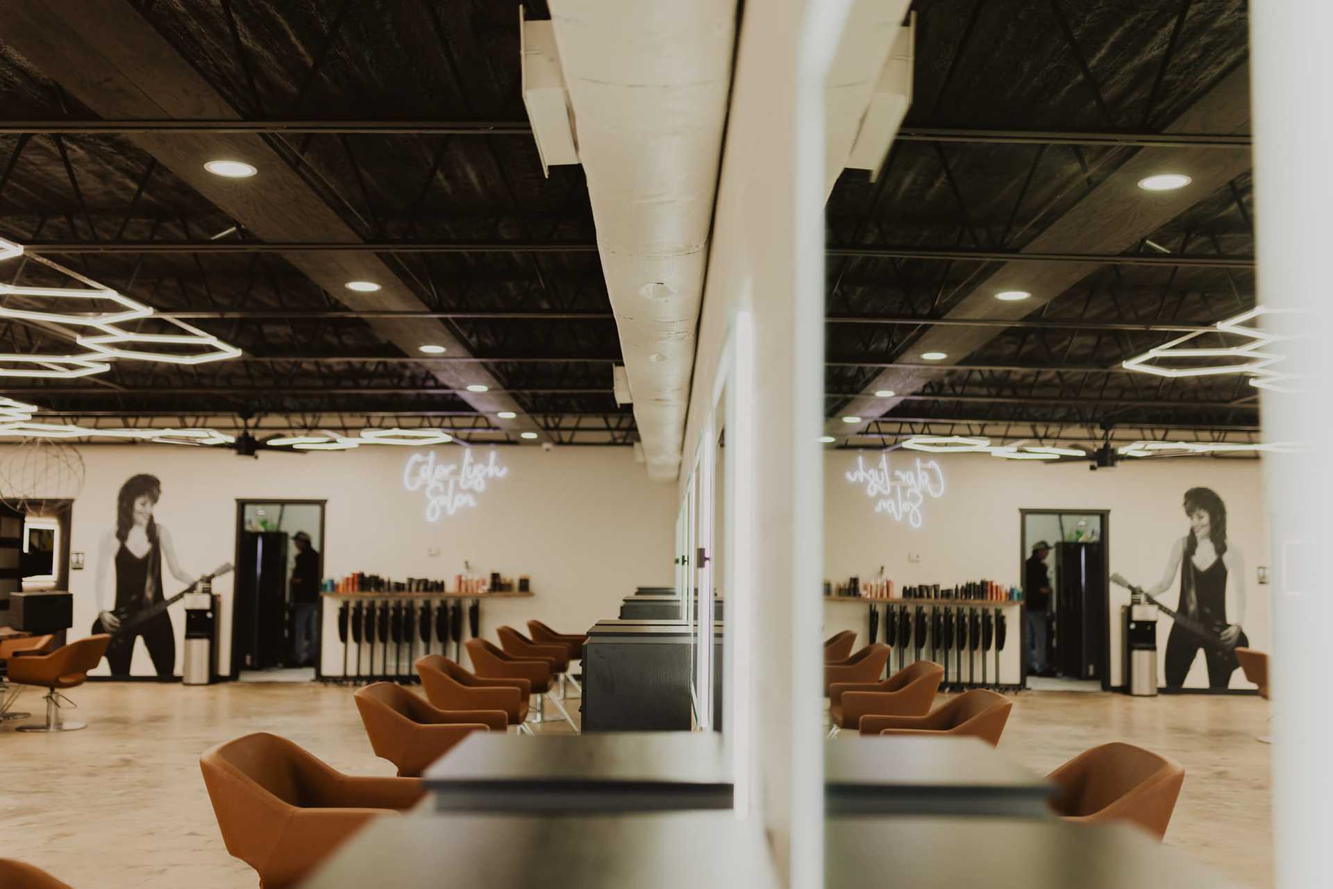 Modern salon interior with brown chairs and neon wall art.