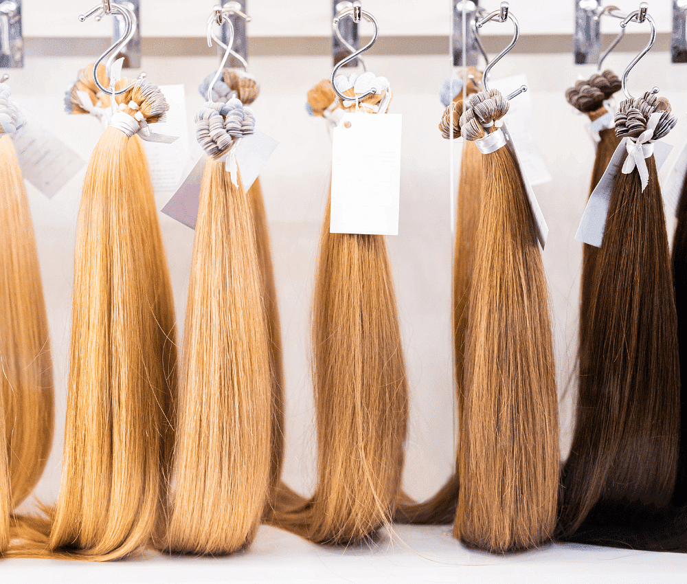 Various shades of hair extensions displayed on a rack.