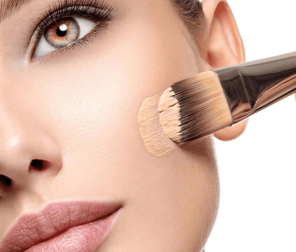 Close-up of foundation application on woman's cheek with brush.